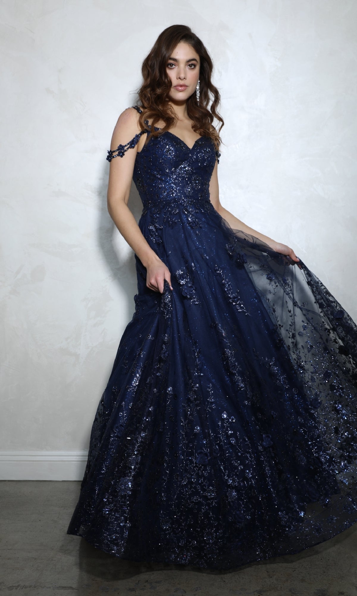 A woman wears the Eureka 9980 Long Glitter-Tulle A-Line Prom Dress with sequins and floral details, posing against a light textured wall.
